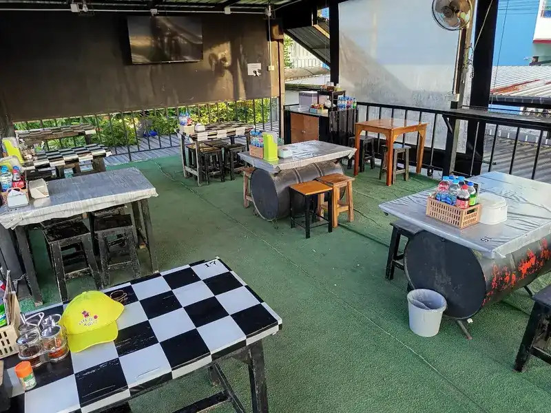 The open terrace with barrel tables, wooden stools, a chequered table and artificial grass