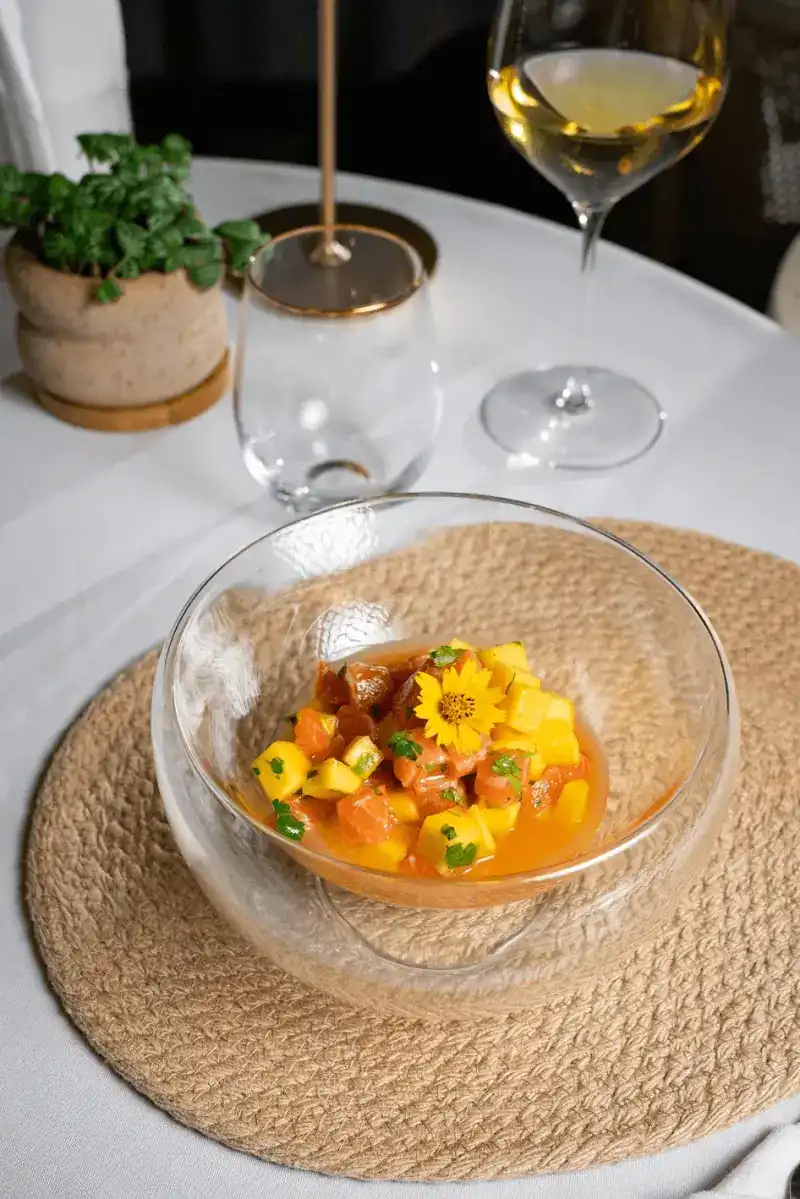 Salmon and mango cubes in a glass bowl with a yellow flower