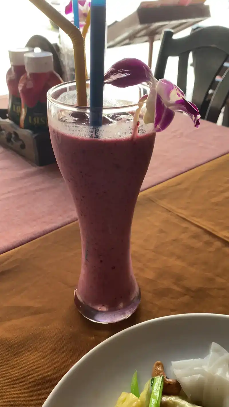 A tall purple smoothie topped with an orchid
