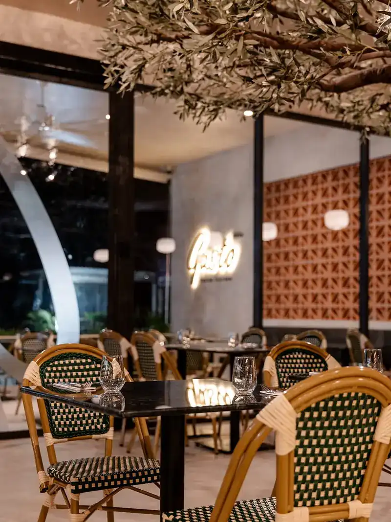 Tables set for the evening, with the lit Gusto sign on the wall