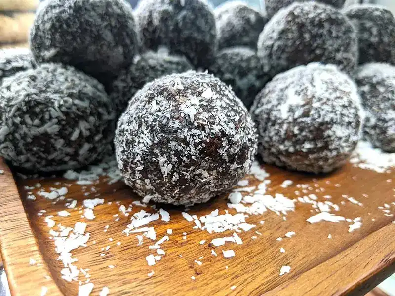 Protein balls rolled in coconut on a wooden board