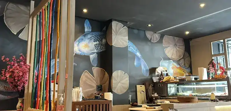 Dining room with painted koi and lily pads on dark walls, beside the sushi counter