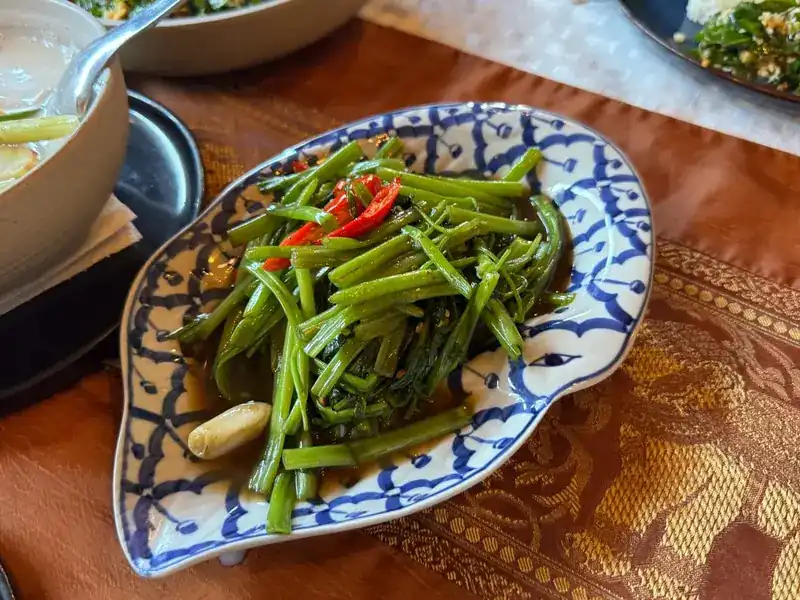 Stir-fried morning glory with garlic and red chilli on a blue-and-white plate