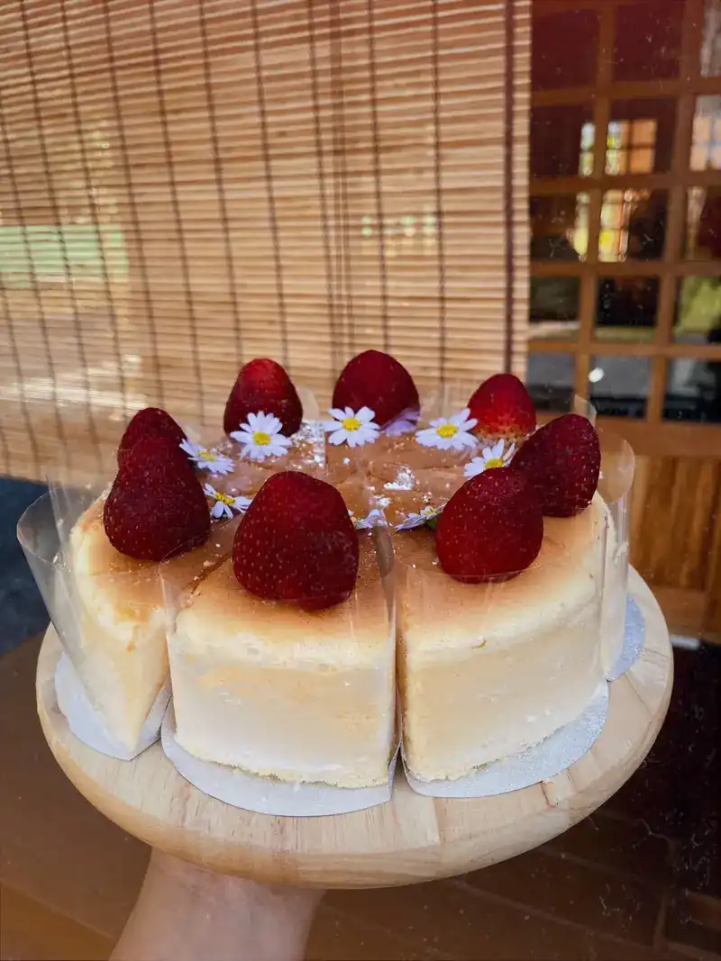 A round cheesecake topped with strawberries and small daisies