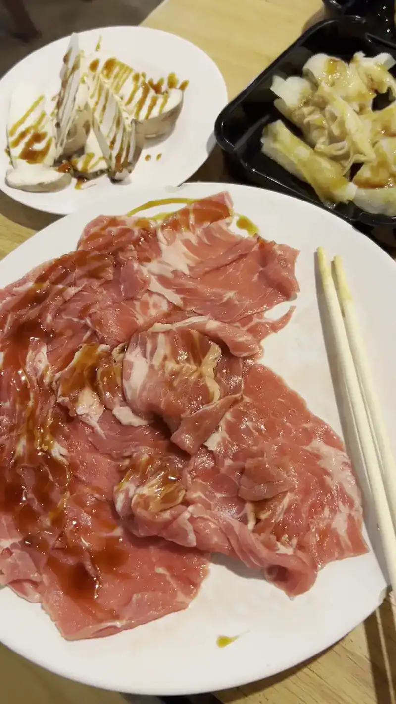 A plate of thin raw slices for the shabu pot, with chopsticks / จานสไลซ์บาง ๆ สำหรับลวกชาบู พร้อมตะเกียบ