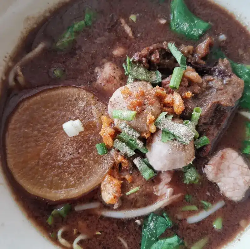Close-up of boat noodles with meatballs, greens, spring onion and fried garlic