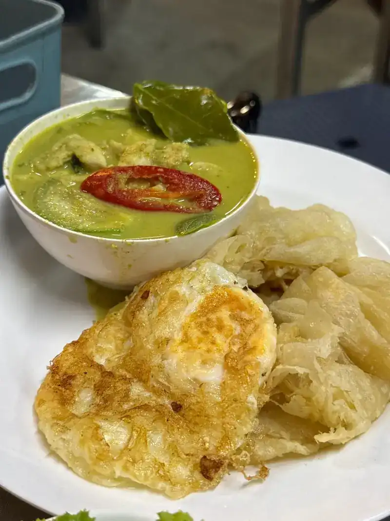 Roti with a bowl of green curry and a fried egg