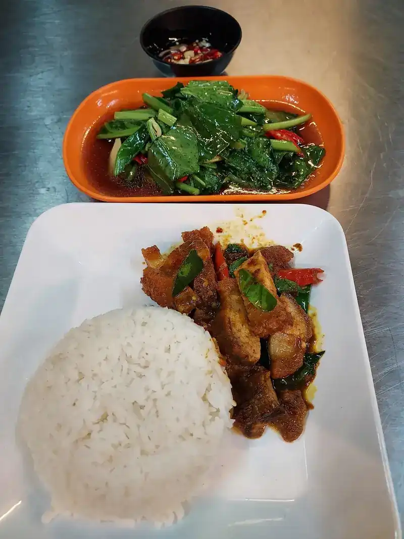 A rice plate with a stir-fry, a side of greens and a small dish of chilli in fish sauce