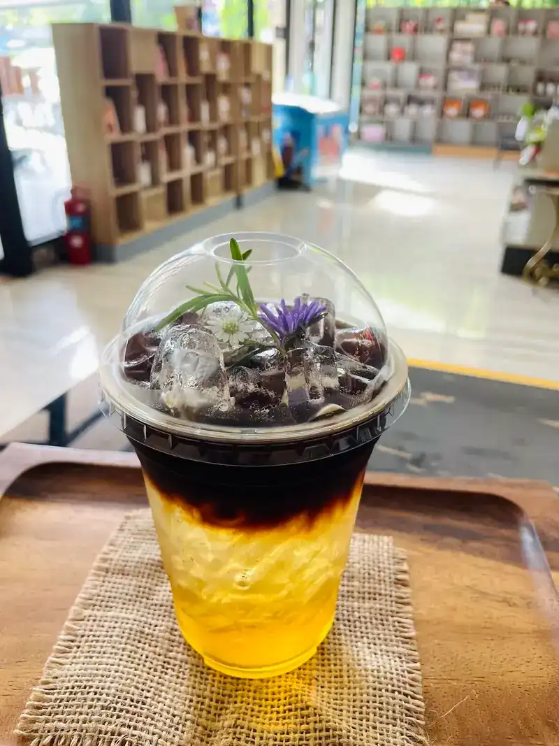 A layered iced coffee drink topped with a purple flower