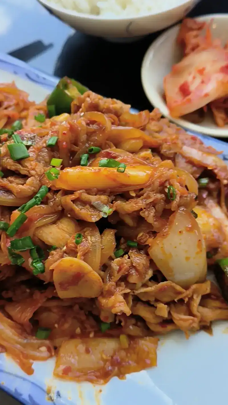 A red, spicy stir-fry with kimchi on the side