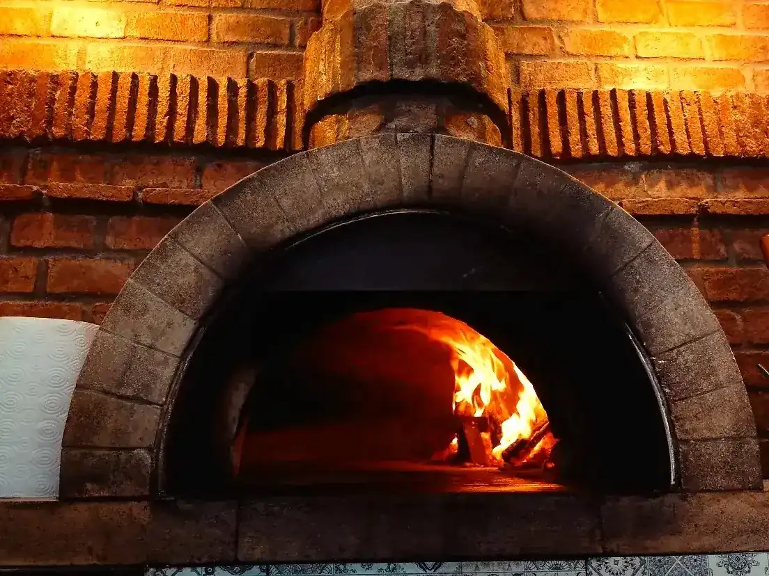 Fire burning inside the brick wood-fired pizza oven at Agli Amici