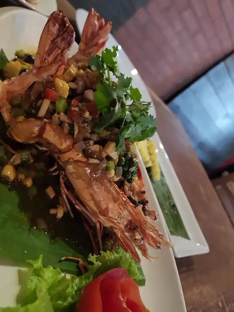 Grilled prawns under a salad of herbs, corn and chopped vegetables