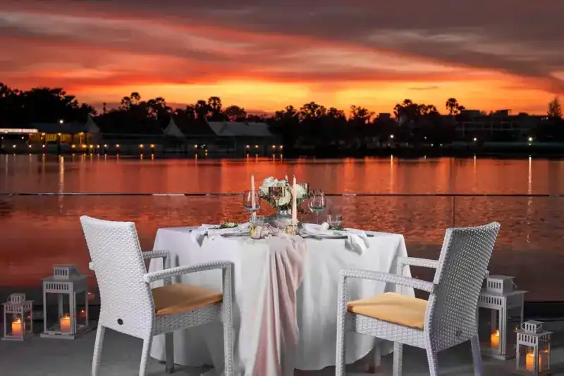 A table for two with candles at the edge of the terrace, the lake red under the sunset