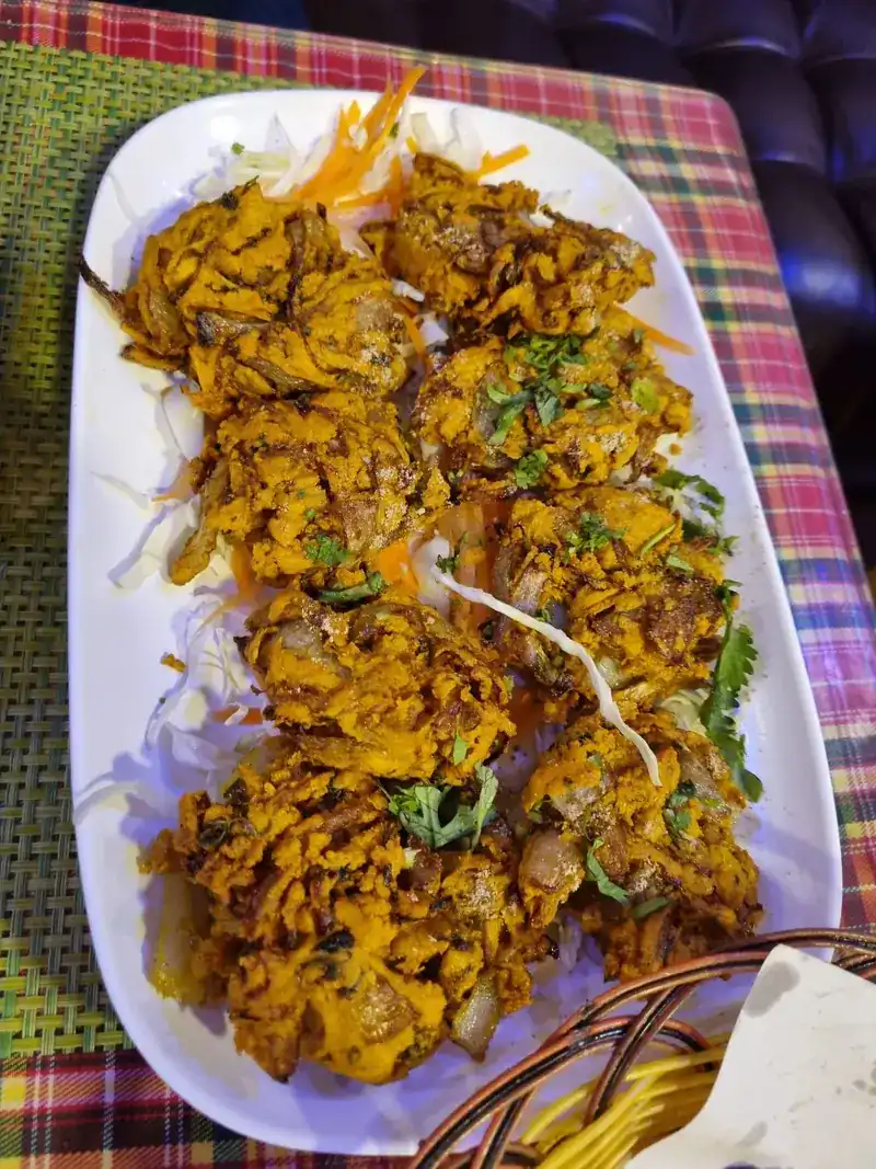 A plate of crisp, spiced fried starters with shredded carrot