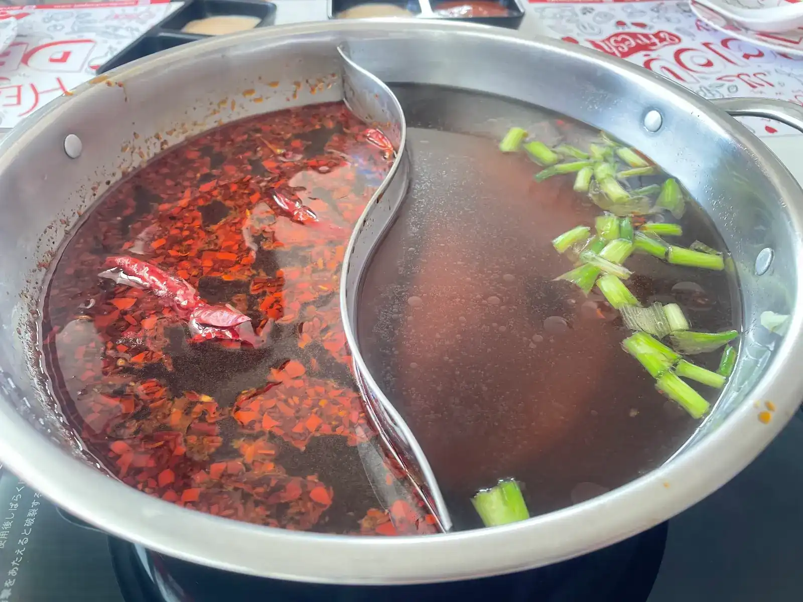 Mala broth and clear broth side by side in a divided hot pot