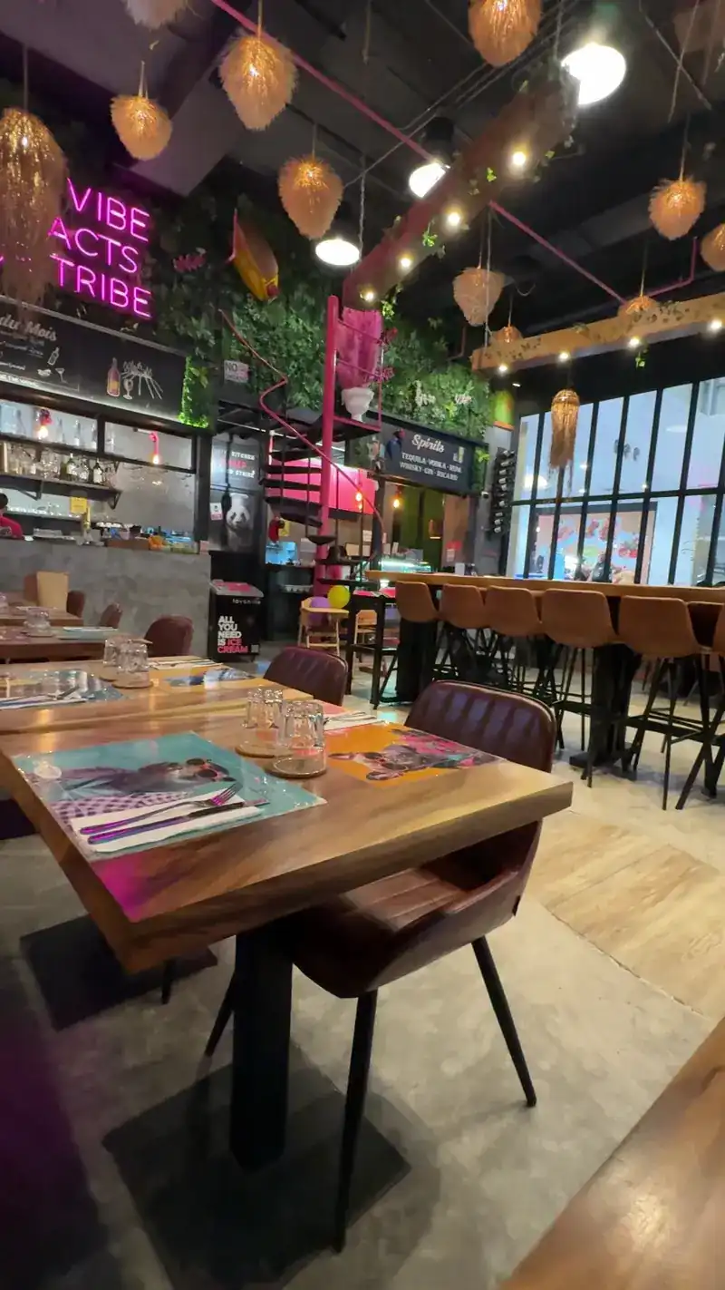 Wooden tables under woven lamps and pink neon lettering / โต๊ะไม้ใต้โคมไฟสานและตัวอักษรไฟนีออนสีชมพู
