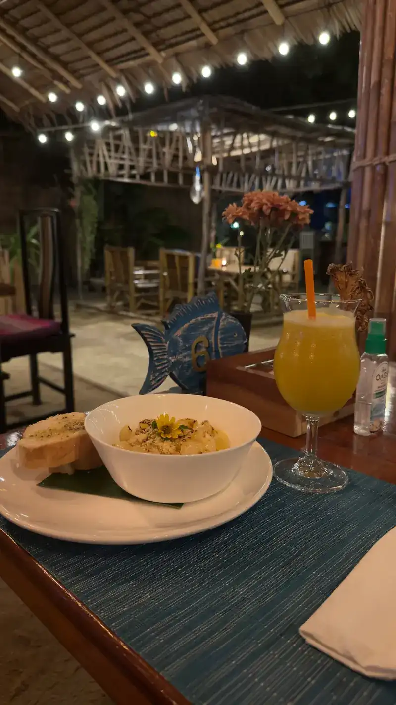 A yellow drink and a bowl on a blue placemat in the bamboo hall at night