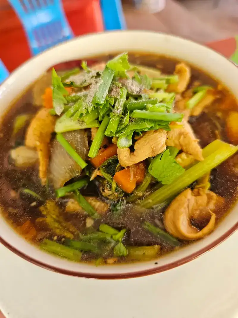 A bowl of dark broth with celery, carrot and coriander / ซุปน้ำเข้มใส่ขึ้นฉ่าย แครอท และผักชี