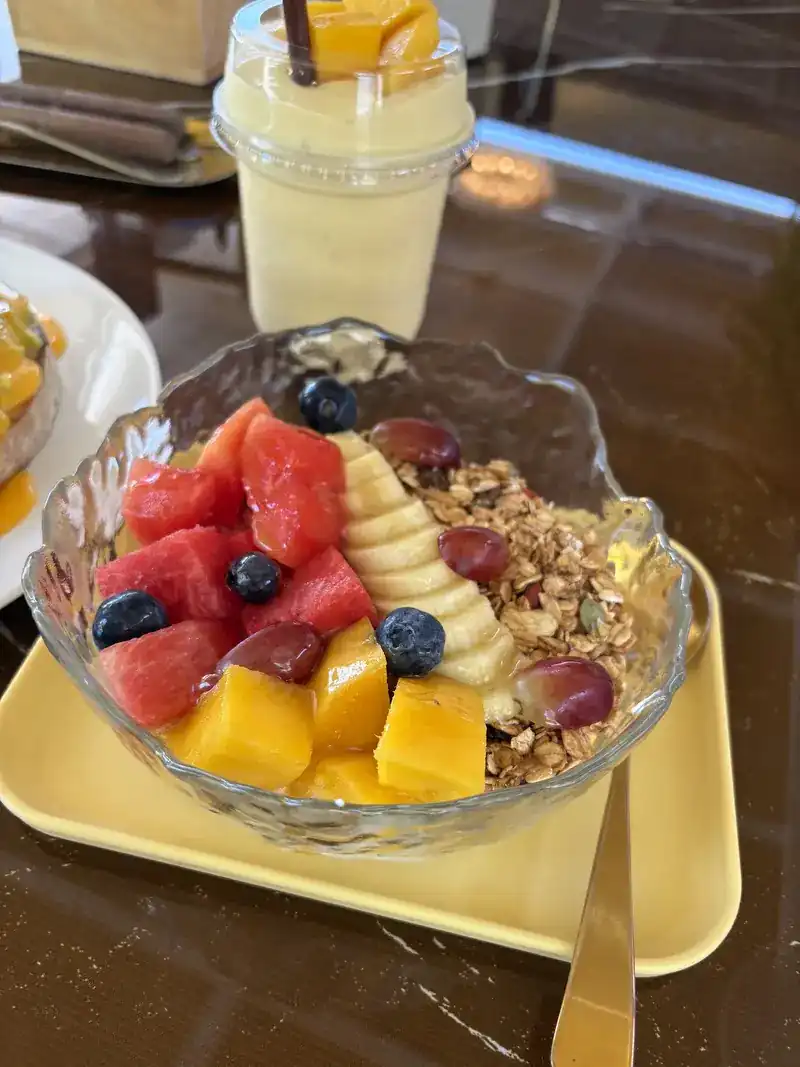 Fruit bowl with watermelon, mango, banana, blueberries and granola, a shake behind