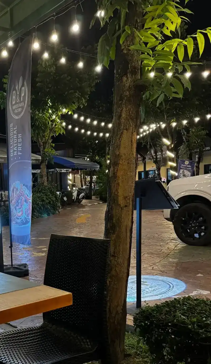 Outdoor tables at night under string lights, beside the B&P flag
