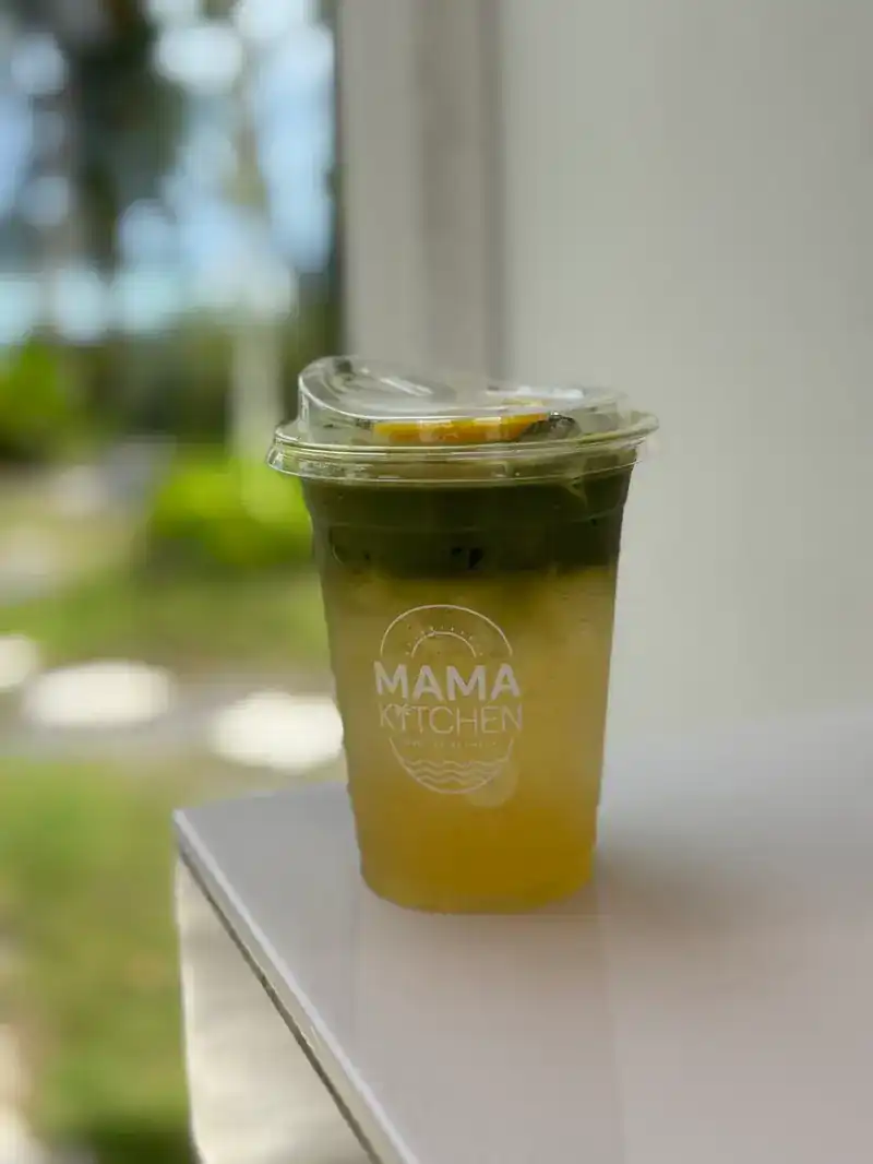 A green and orange layered iced drink in a Mama Kitchen cup
