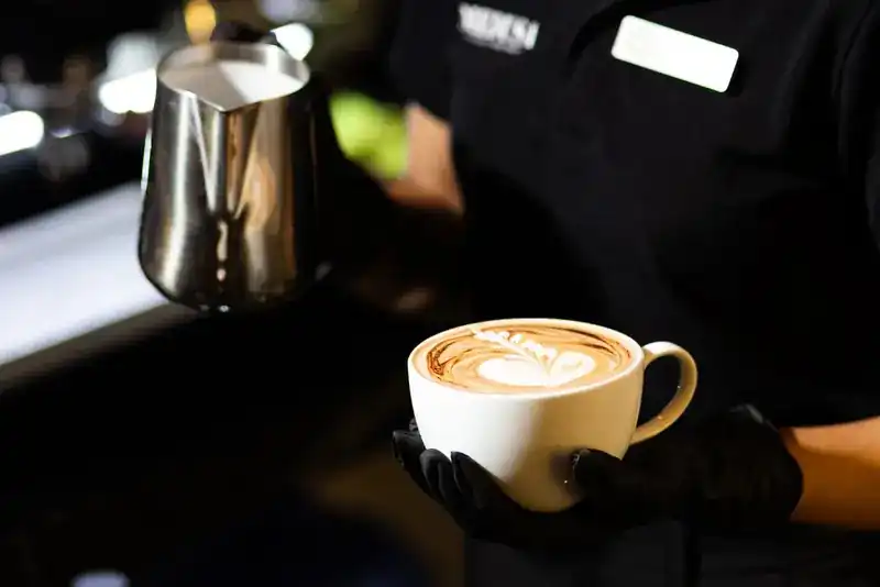 A latte with leaf art, just poured at the coffee bar
