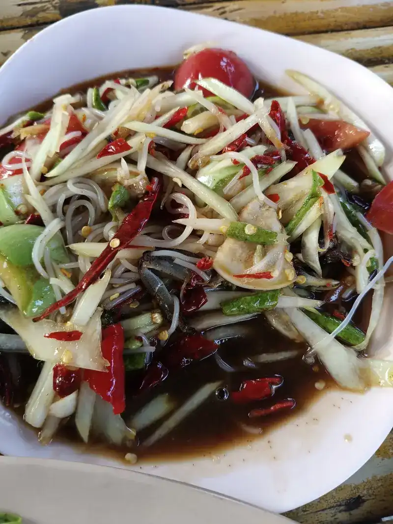 Som tam with noodles, crab and dried chillies on a bamboo table
