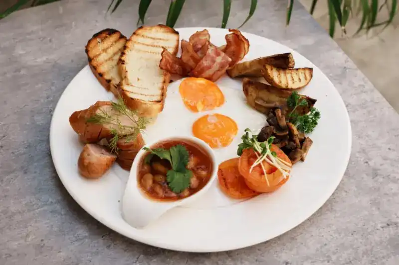 English breakfast: eggs, bacon, sausage, beans, mushrooms and toast