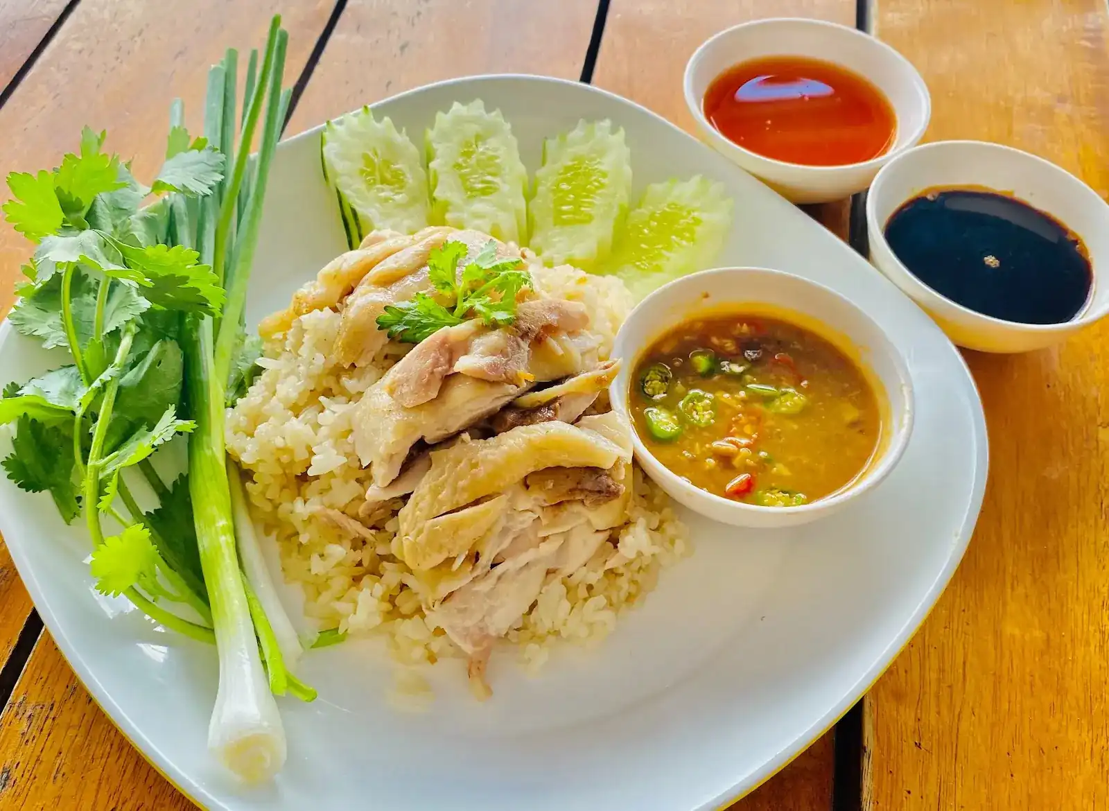 Chicken rice: sliced chicken on rice with cucumber, spring onion, coriander and three dipping sauces