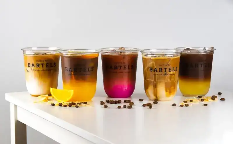 Five iced coffee drinks in Bartels cups, layered with orange, beetroot and milk