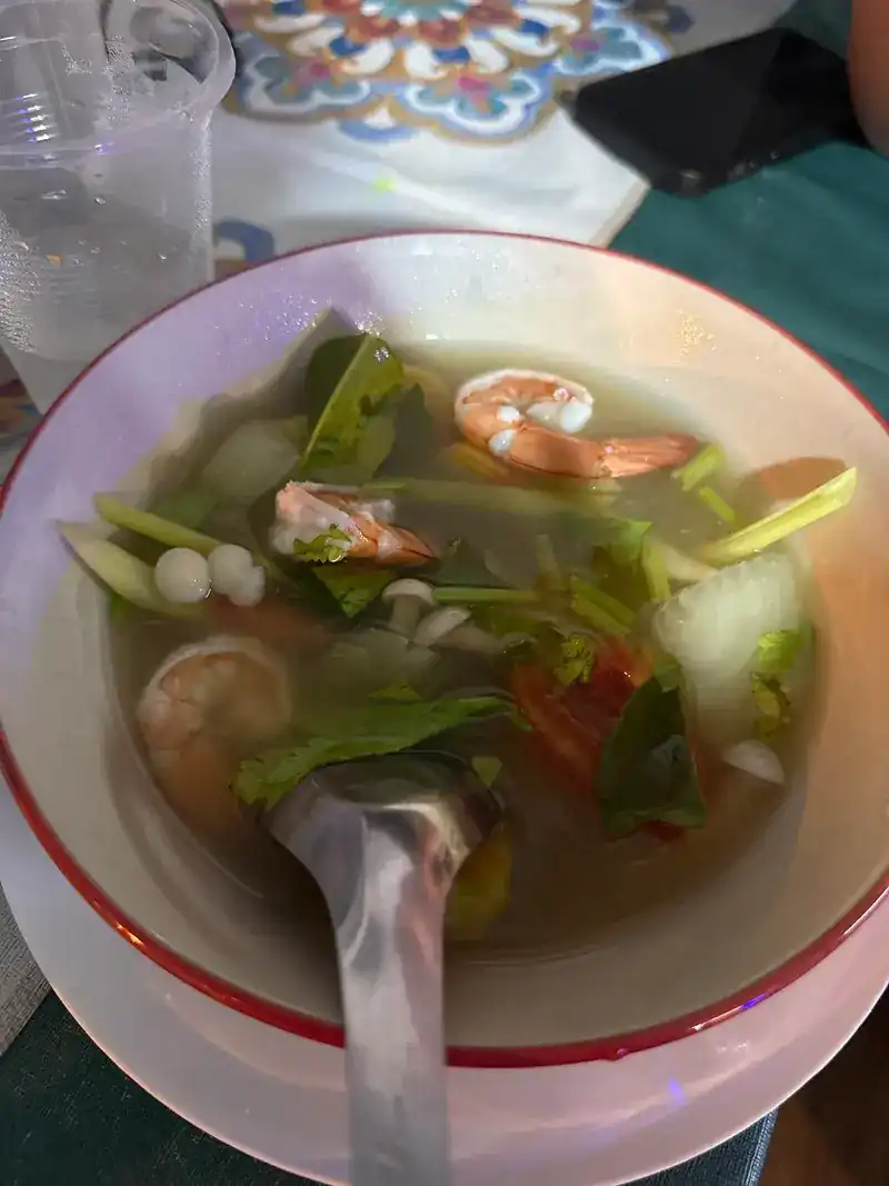 A clear soup with prawns, tomato and greens