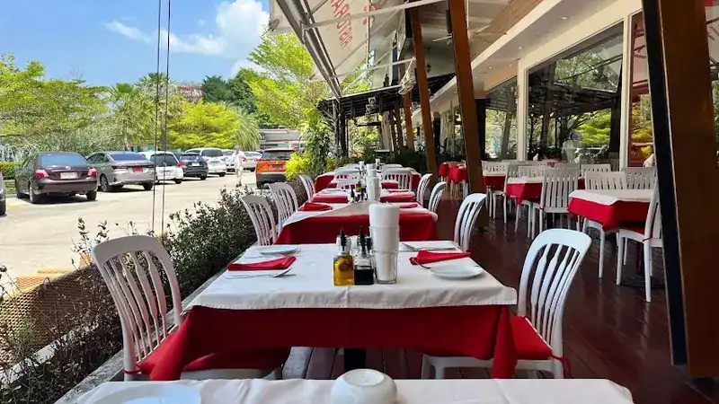 Terrace tables laid with red and white cloths, trees beyond