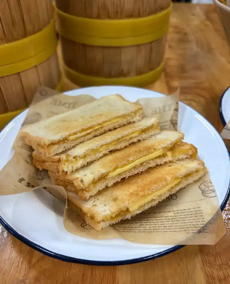 Toast cut into fingers on a plate, bamboo steamer baskets behind