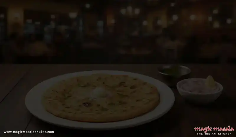A stuffed flatbread topped with butter on a white plate