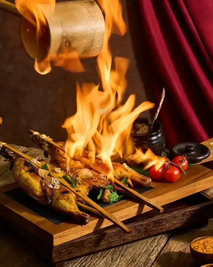 Turmeric chicken on bamboo skewers in a burst of flame