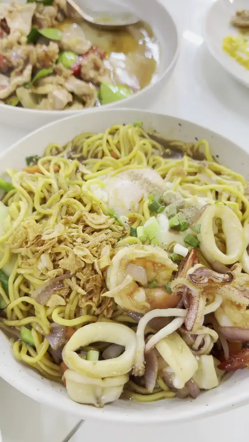 Yellow noodles with squid rings, prawns and fried garlic