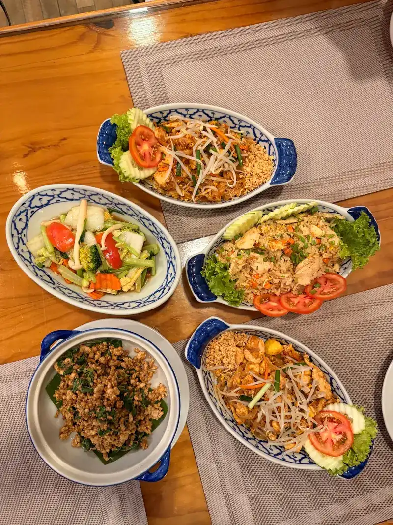 Pad thai and other dishes on a wooden table, seen from above