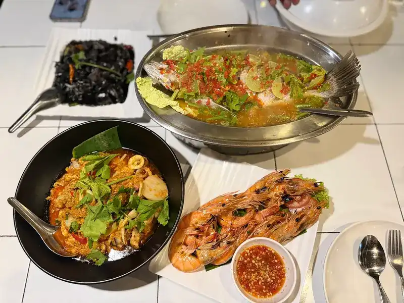 A table with steamed fish in lime and chilli, grilled prawns and a spicy bowl