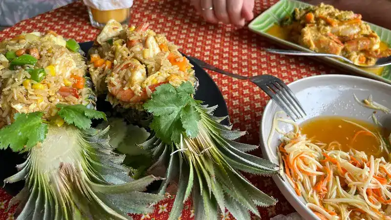 Rice baked in pineapple halves next to papaya salad