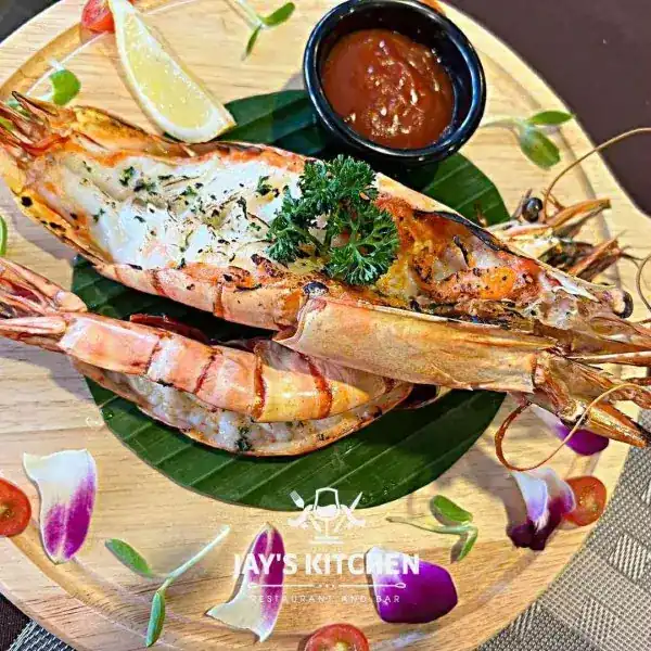 Grilled prawns on a banana leaf with lemon and a dipping sauce