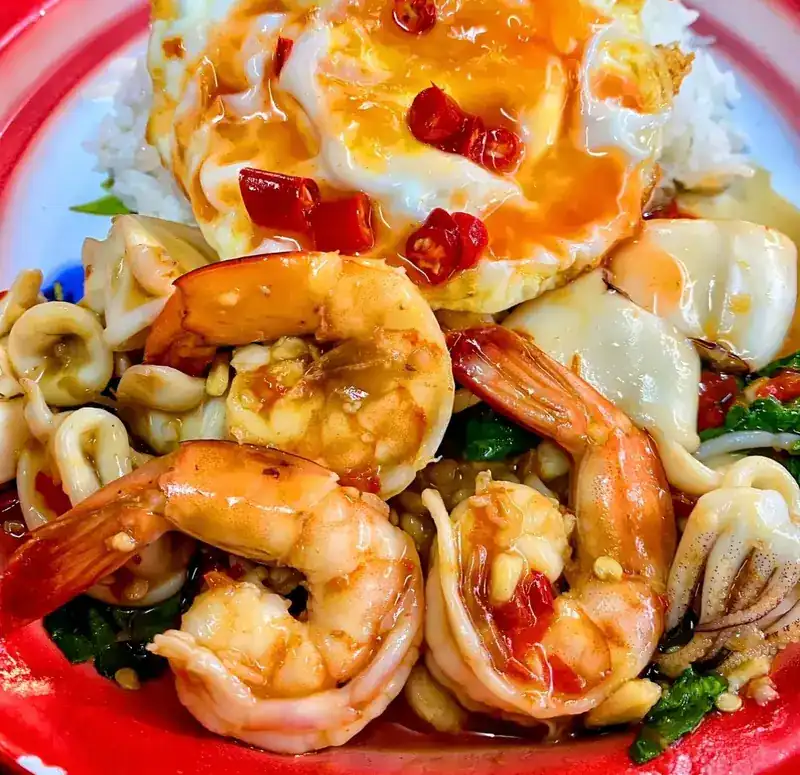 Shrimp and squid stir-fried with holy basil and chilli, with a fried egg on rice