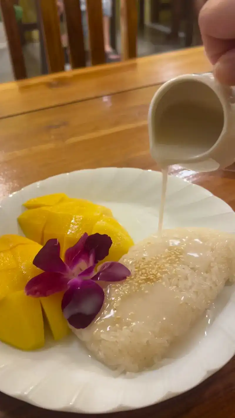 Mango with sticky rice, coconut cream being poured over it