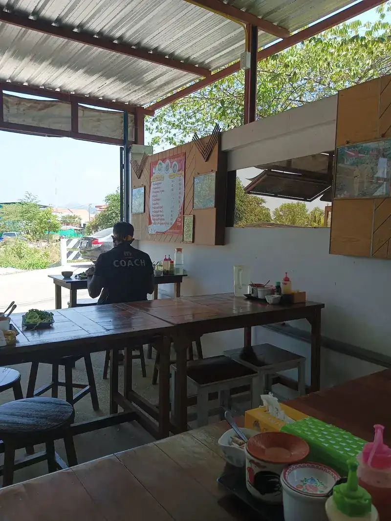 Inside the open-sided shop: wooden tables, stools and the board on the wall