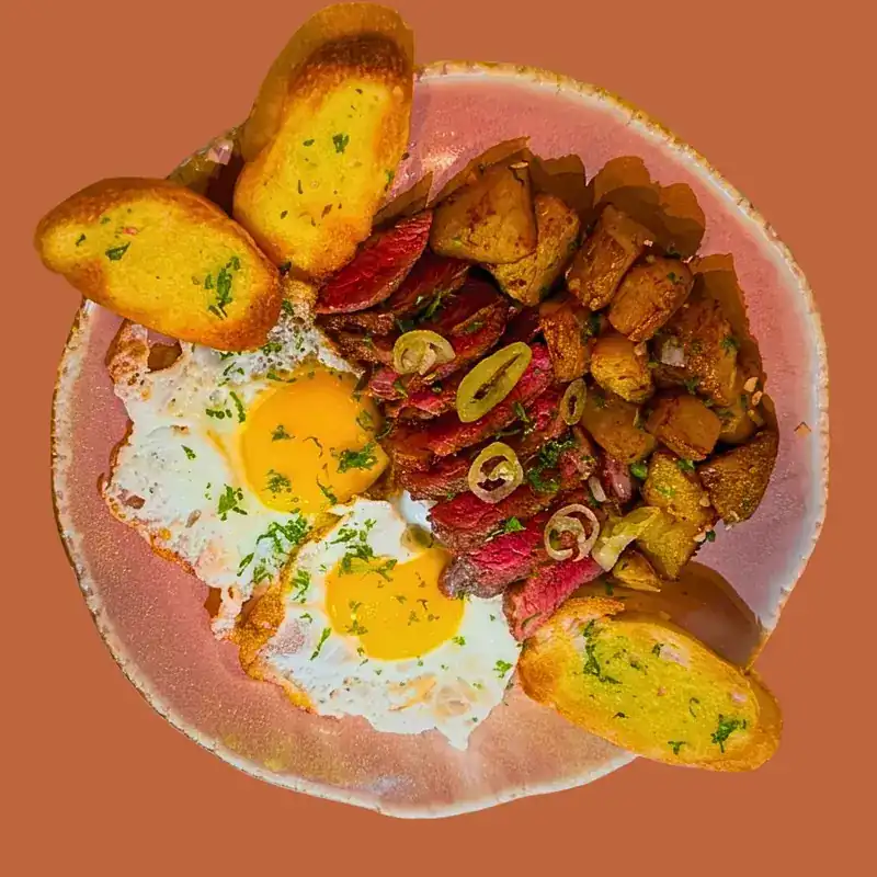Sliced Angus beef with fried eggs, roasted potatoes and toasted bread