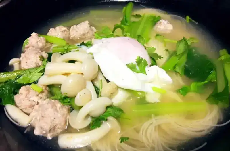 Fine noodles in clear soup with minced pork balls, mushrooms, greens and a poached egg