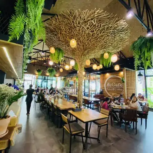 A woven tree hung with round lanterns and ferns under the café roof