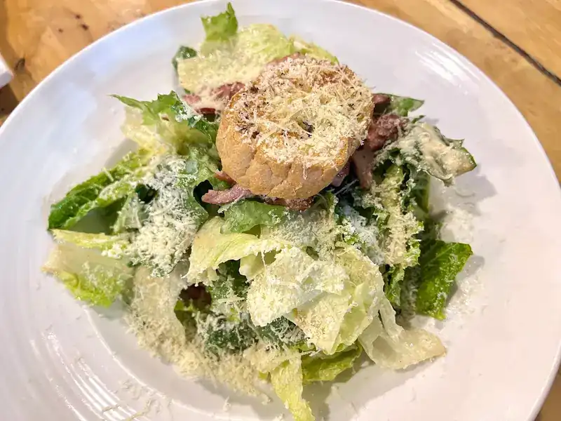 Cos lettuce salad with grated cheese and a round of toasted bread