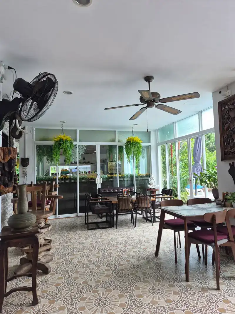 The dining room with patterned tiles, ceiling fans and hanging plants