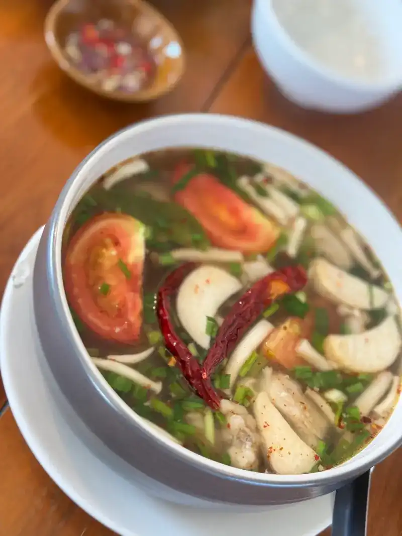 Tom yum in a clear broth with tomato, mushroom and dried chilli