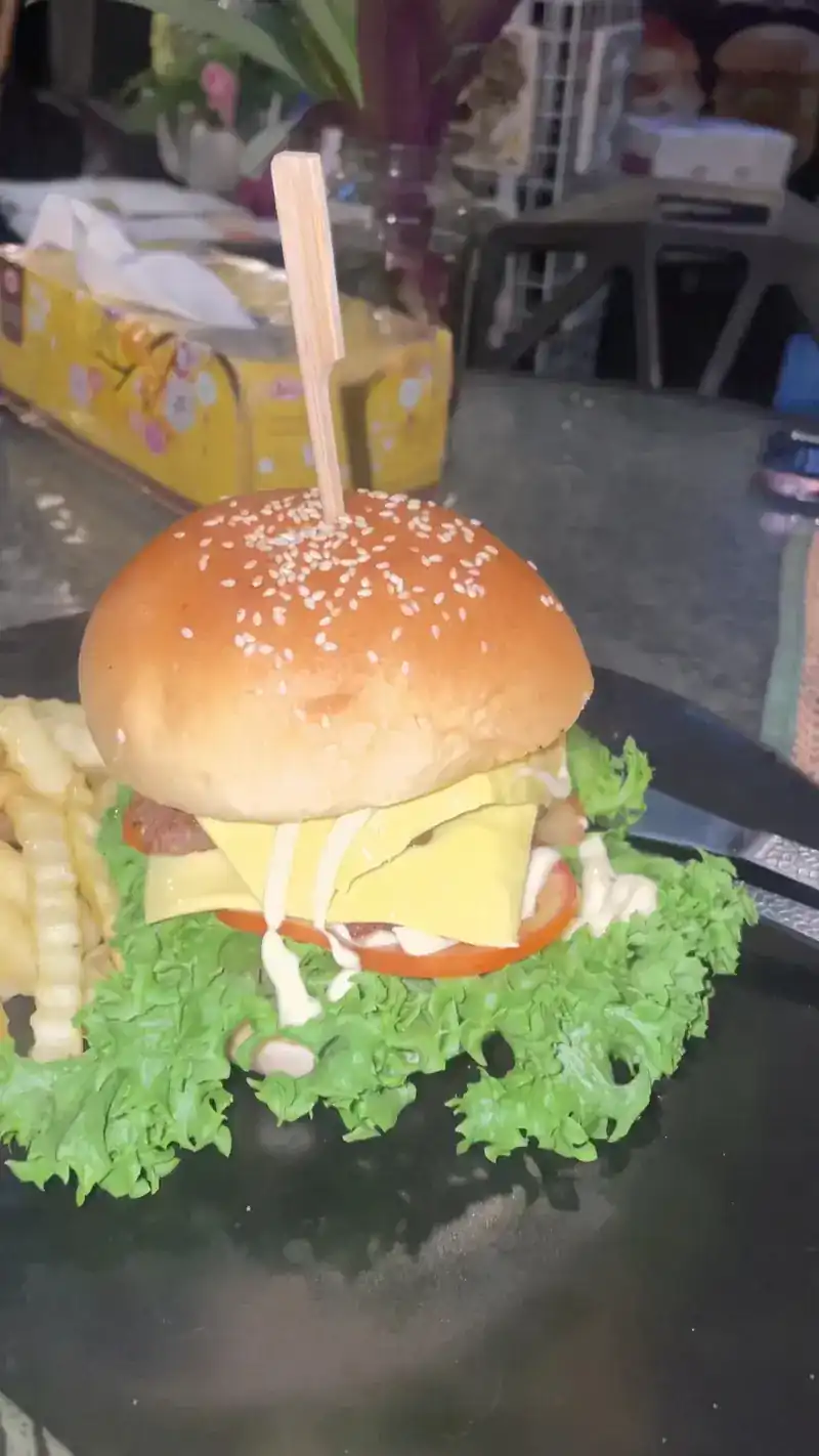 Tall cheeseburger with tomato and curly lettuce